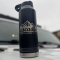 Black water bottle with 'Cascadia Overland Co.' logo on a white surface