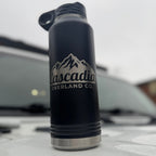 Black water bottle with 'Cascadia Overland Co.' logo on a white surface