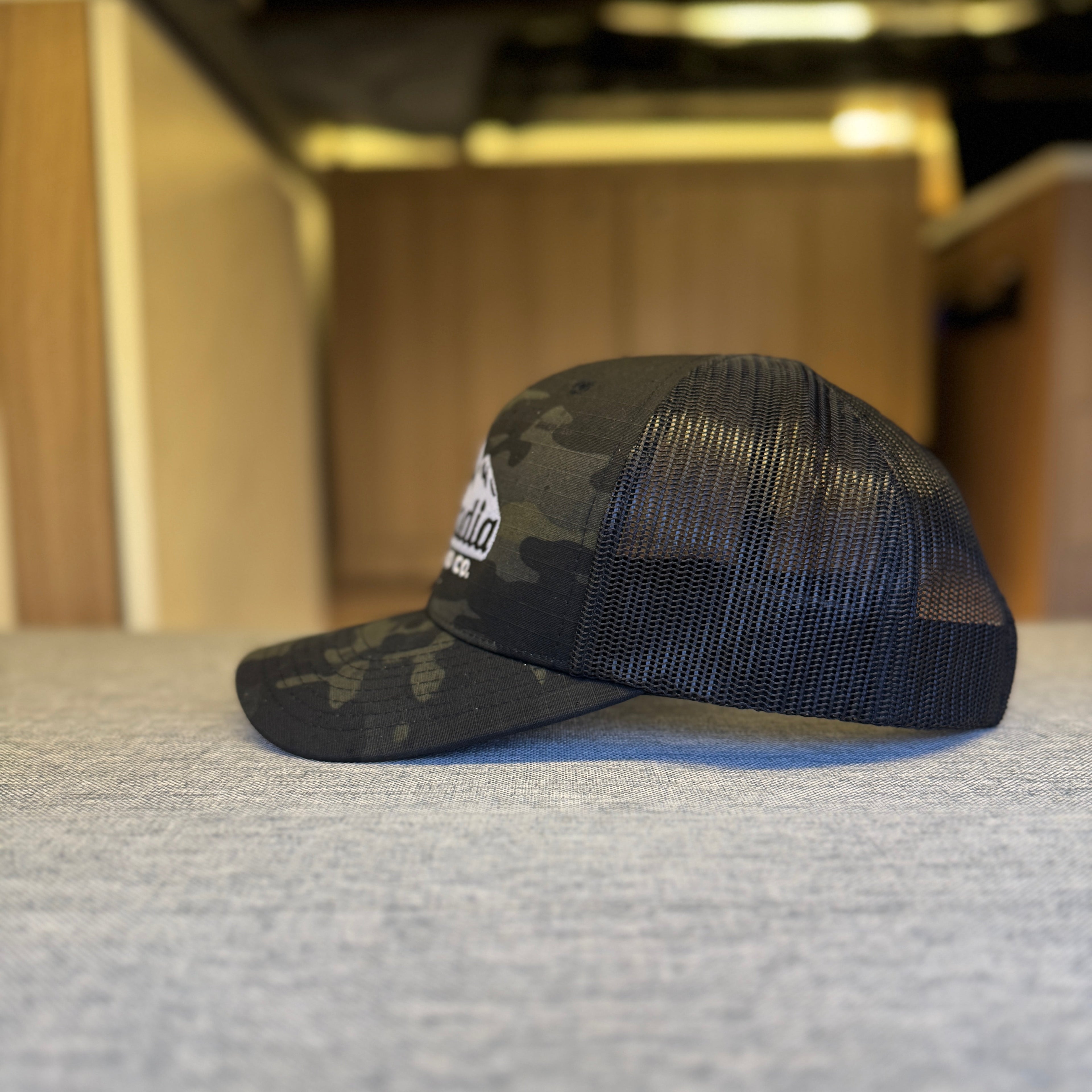 Black mesh cap with camouflage visor on a textured surface