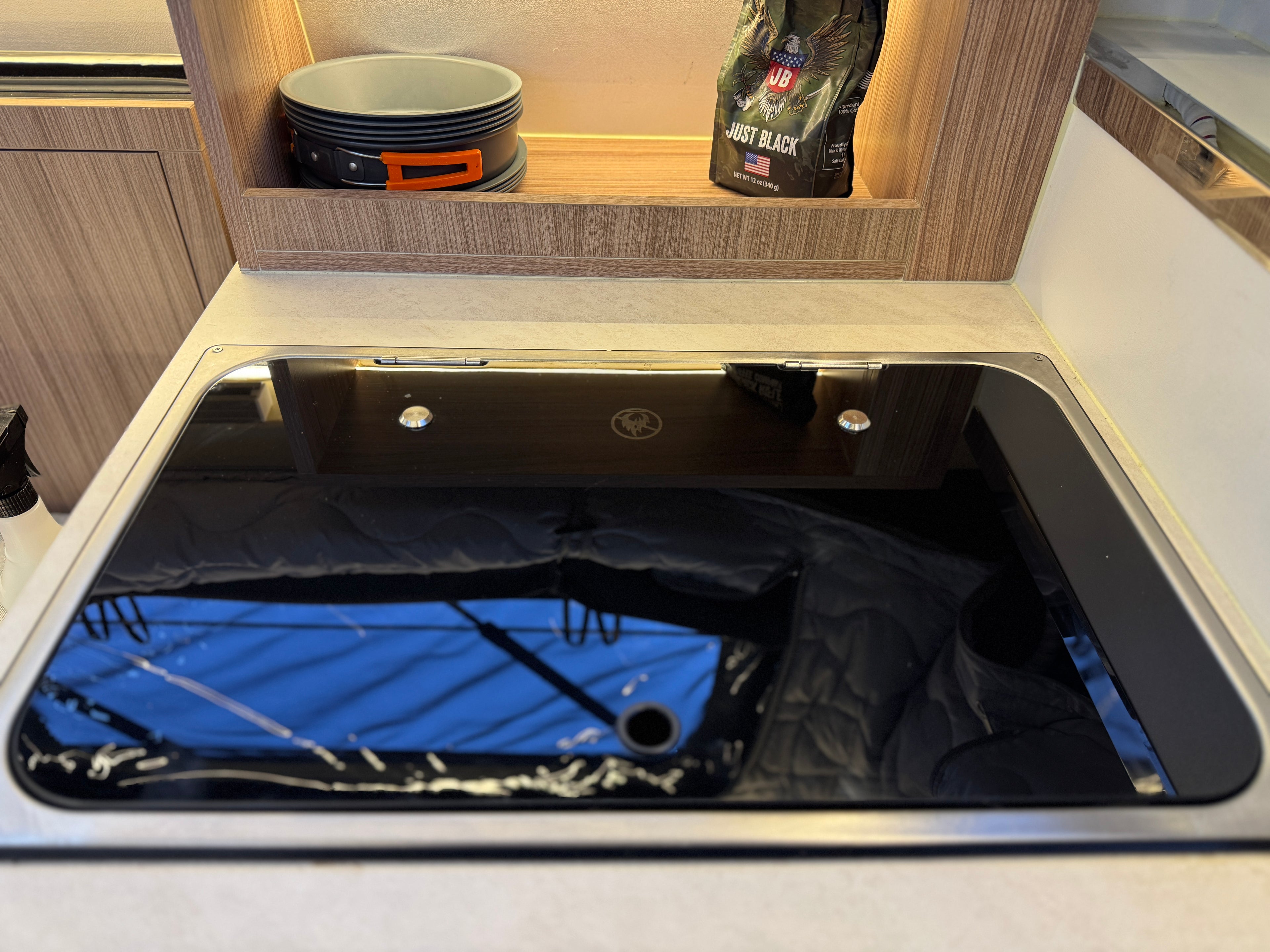 Stainless steel sink in a kitchen setting with a reflection of a blue surface.