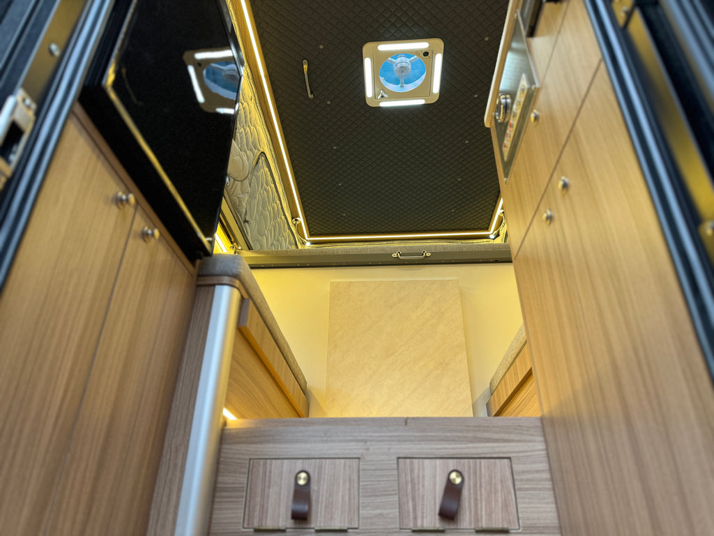 Wooden staircase with metal railing inside a vehicle or building.