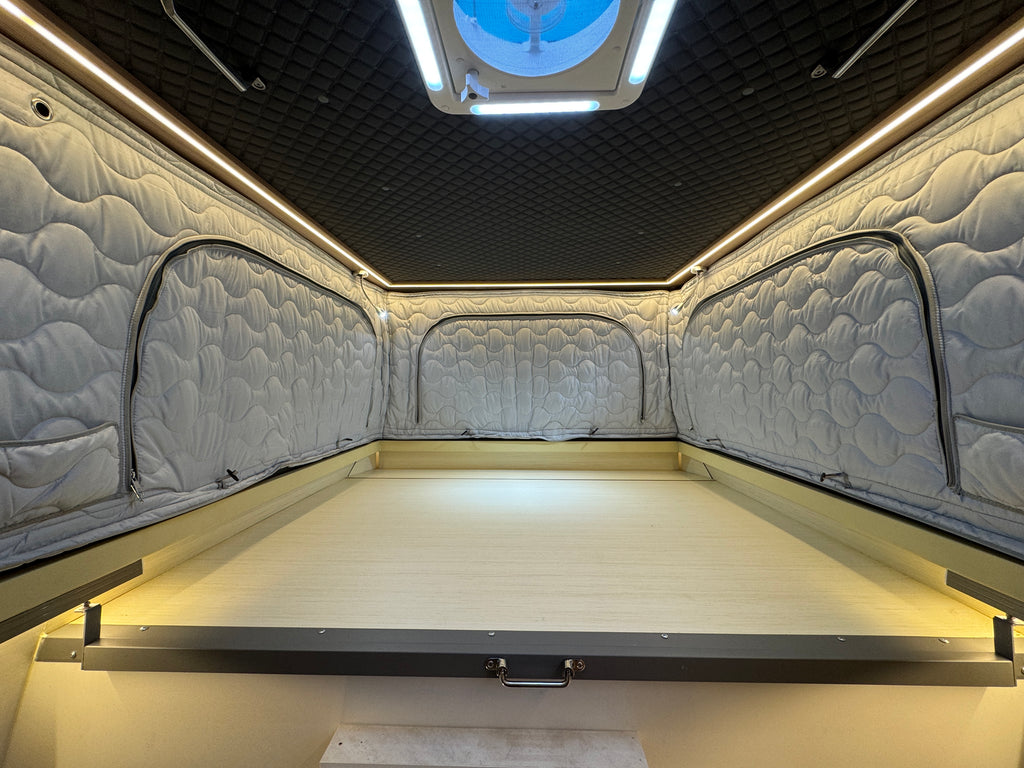 Interior of a vehicle with quilted walls and a flat bed area.