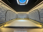 Interior of a vehicle with quilted walls and a flat bed area.