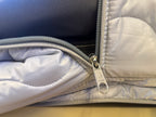 Close-up of a silver zipper on a gray garment with a visible brand logo.
