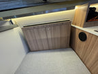 Compact kitchen area with wooden cabinets and a countertop inside a vehicle or small living space.